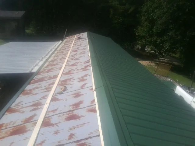 Old rusted panels beside newly installed green metal roofing — Wind Damage Roof Repair by Roofing Brothers in New Stanton