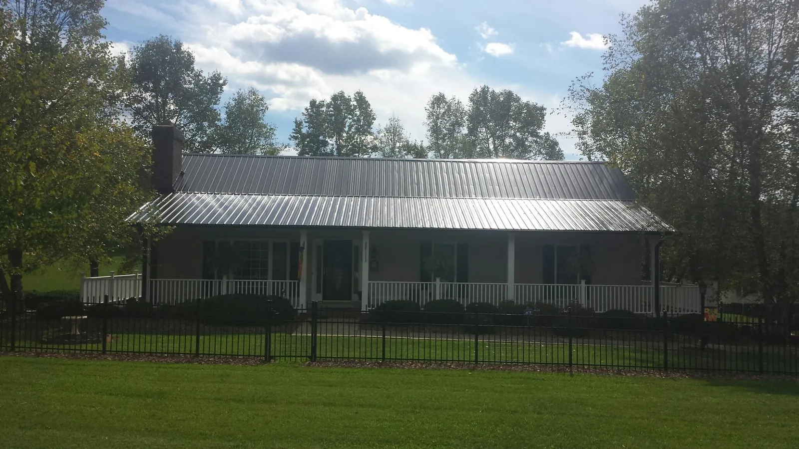 Gray metal roof on a brick ranch with a full width front porch — Gutter Guard Installation work by our crew in New Stanton
