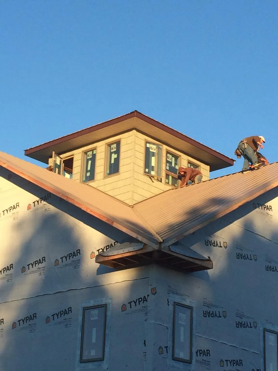 Roofers working around a rooftop cupola on a new metal roof at sunset — Roof Waterproofing in New Stanton by Roofing Brothers
